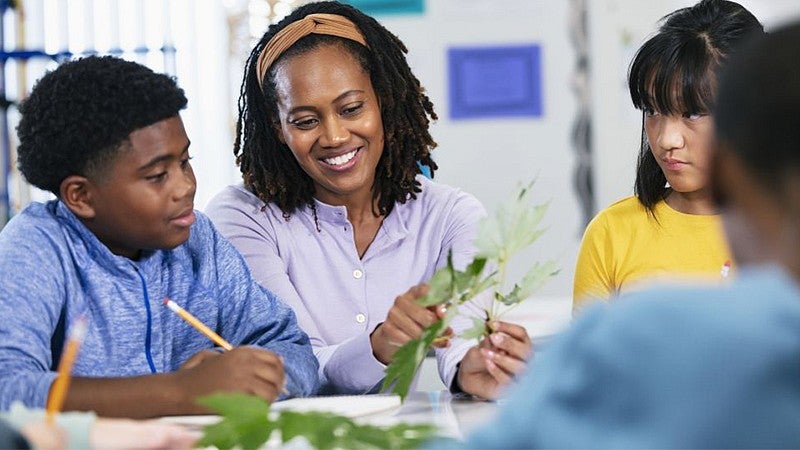 individual sitting talking with students sitting at a table