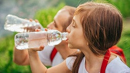 image of two individuals drinking water from water bottles