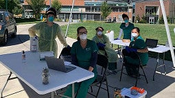 image of UO students in masks under a tent doing COVID testing