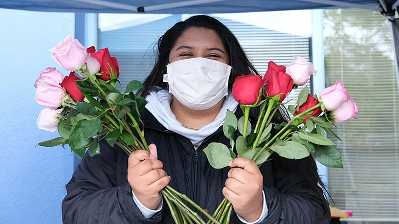 image of person wearing mask holding long stem roses