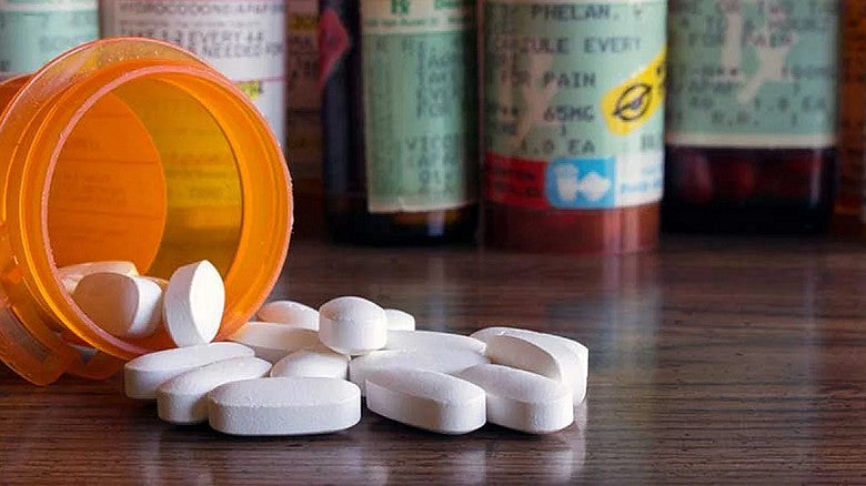 image of pill bottle with white pills spilling onto a table